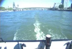 Rear stern camera view showing the white propeller wake, stern bollards, and bridge astern.