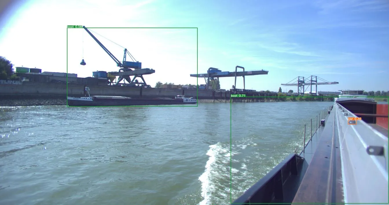 River port frame with a tall green boat 0.58 box grouping crane and barge, plus car 0.30 on deck.