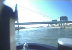 Forward bow camera view showing the cable-stayed bridge ahead across the river and bow housing.